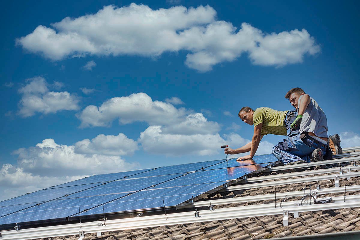 Installing solar photovoltaic panel system. Solar panel technician installing solar panels on roof. Alternative energy ecological concept.